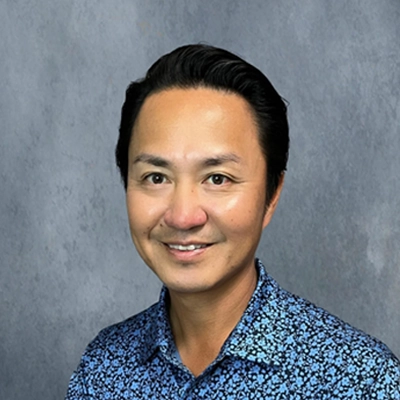 Dr. David Choe smiling in a blue button up.