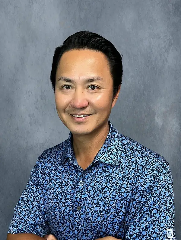 Dr. David Choe smiling in a blue floral button up.